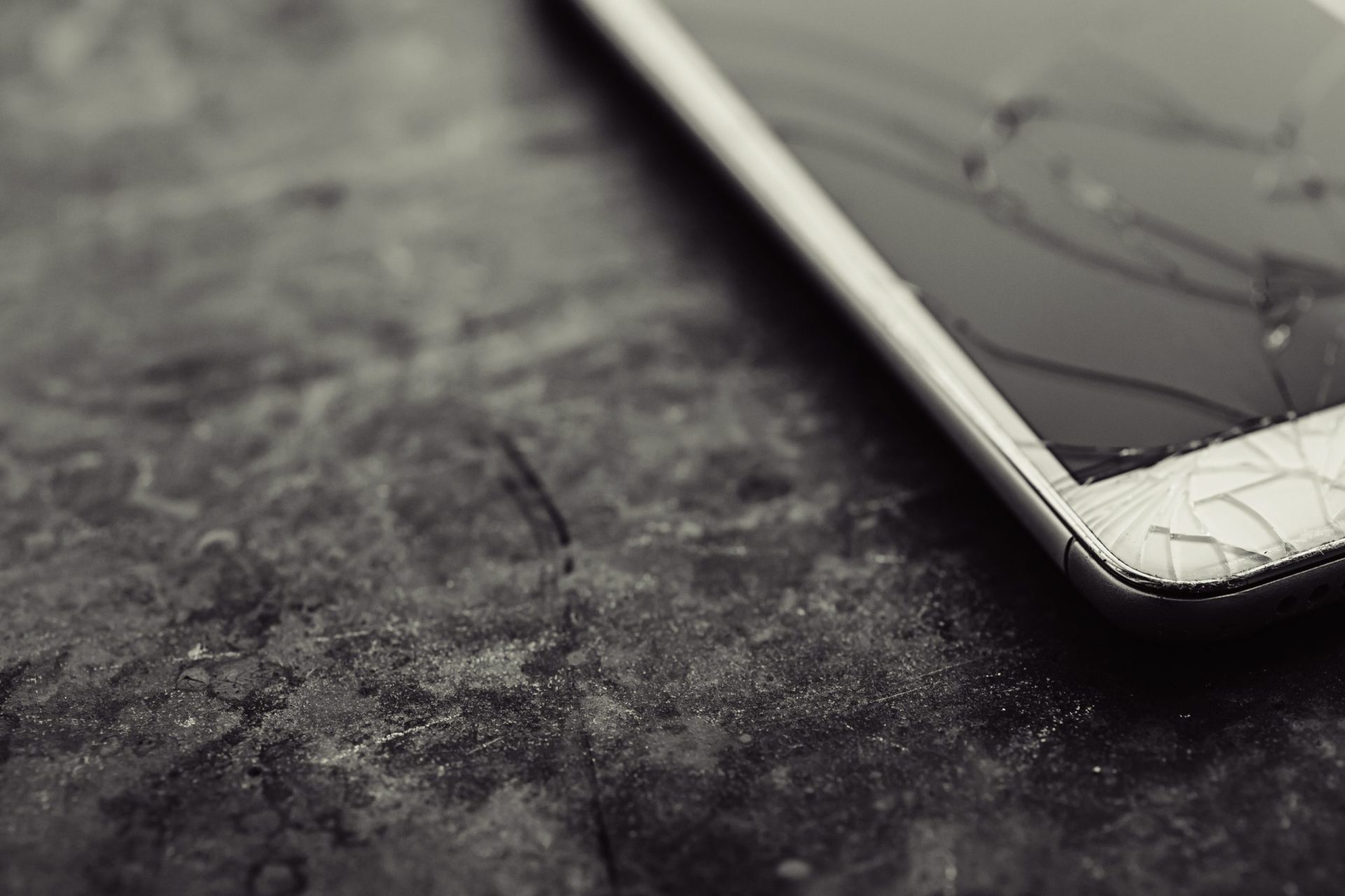 Smart phone with broken screen on dark background. Close-up.