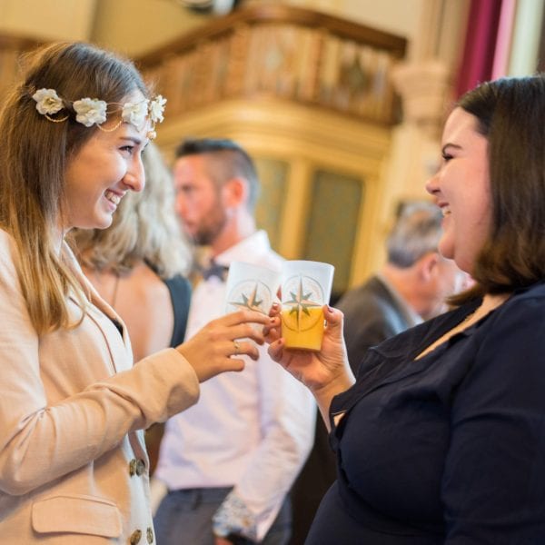 Filles qui trinquent avec des ecocups personnalisés à un mariage.