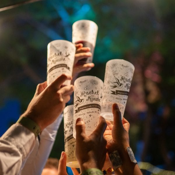 Invités qui trinquent avec des ecocups personnalisés à un mariage.