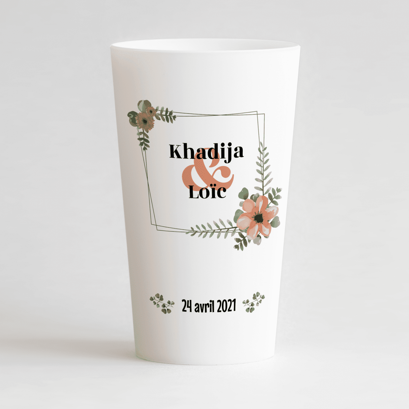 Un ecocup blanc de face avec un thème mariage, un cadre floral autour des prénoms des mariés et la date du mariage.