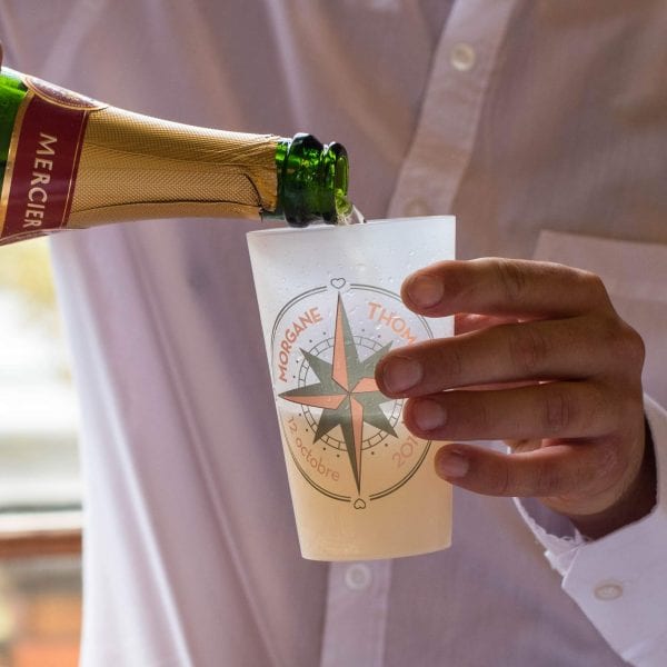 Un ecocup givré dans lequel un invité de mariage est en train de servir du champagne.