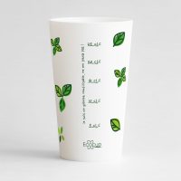 Un ecocup blanc de dos avec une graduation verte, entourée des feuilles et une graduation