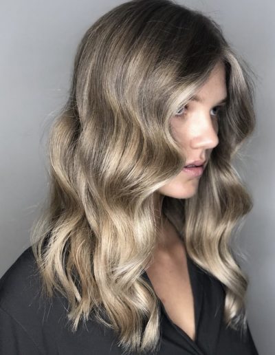 Girl with Natural balayage hair colour with face frame highlights and a long layered haircut with a soft wavy hairstyle