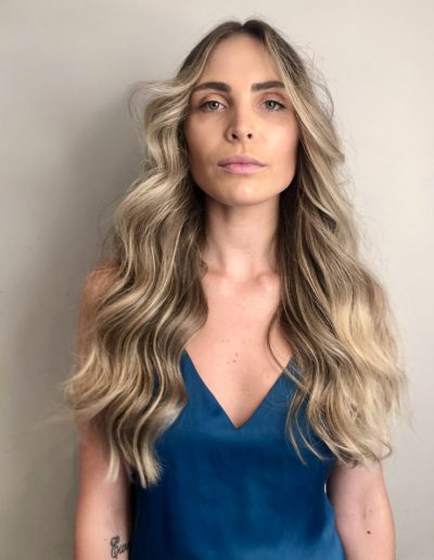 Girl with vanilla blonde balayage hair colour and face frame highlights with curly center part hair style and long hair