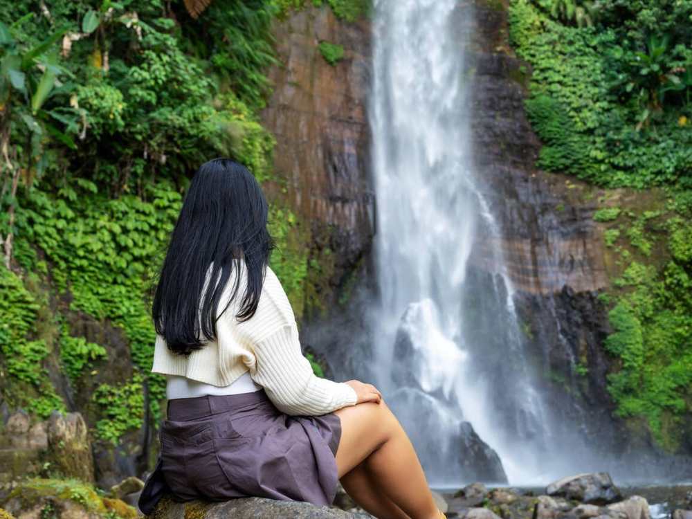 Woman enjoyng the peaceful vibes and views of Gitgit waterfall 