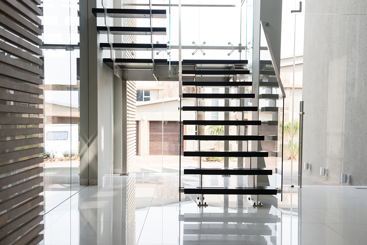 a steel staircase with timber treads and glass balustrades in a contemporary home
