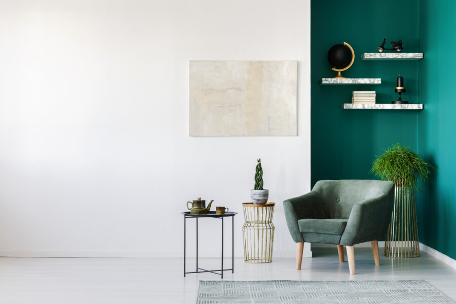 White and green living room interior with armchair, plants, teapot set and book shelves