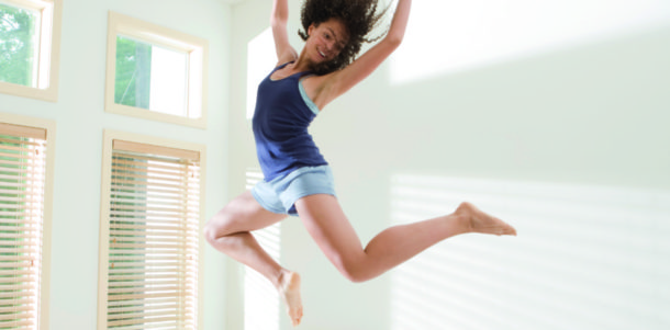 Attractive Young Woman Jumping Energetically on Bed