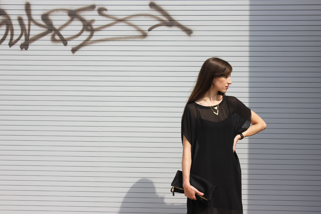 Style Bee in a black sheer dress with a black clutch.