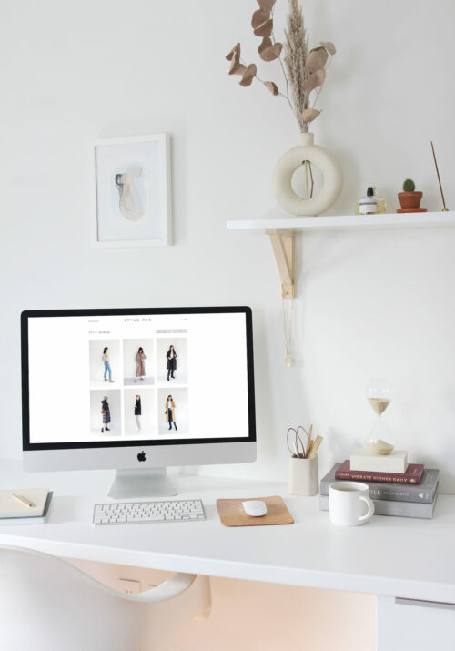 Bright white home office with a floating shelf, iMac, stacked books and artifacts.