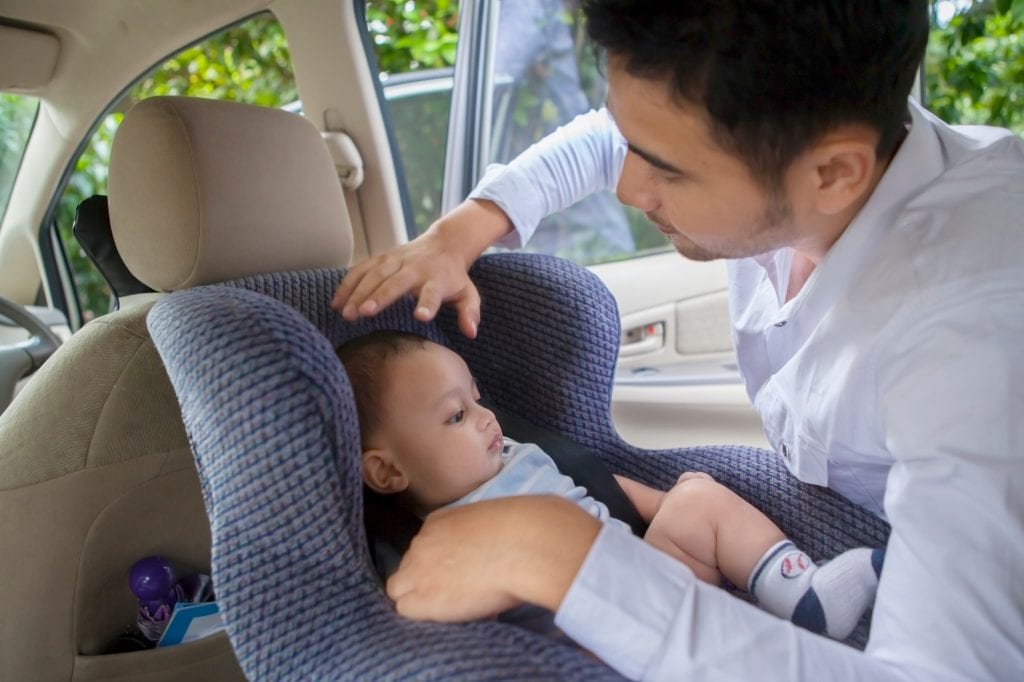 father-putting-child-in-carseat