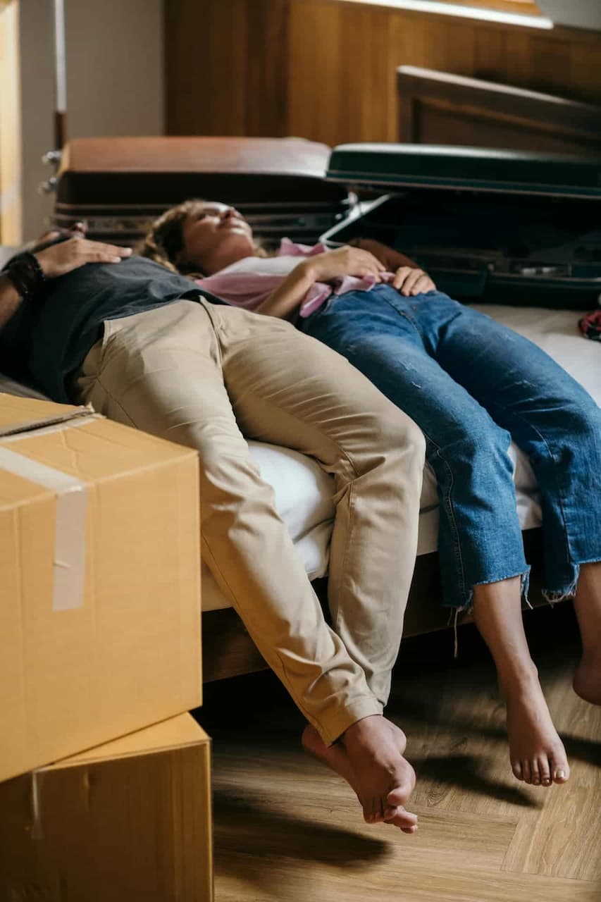 couple on bed surrounded by moving boxes