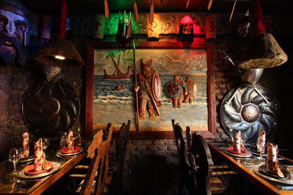 Bar Restaurante con estética vikinga. Se ven mesas y sillas talladas en madera, con escudos y cuadros vikingos.