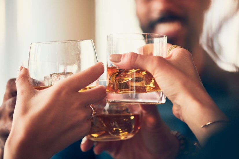 Se ven las manos de tres personas con tres vasos con ron y hielo, haciendo un brindis.