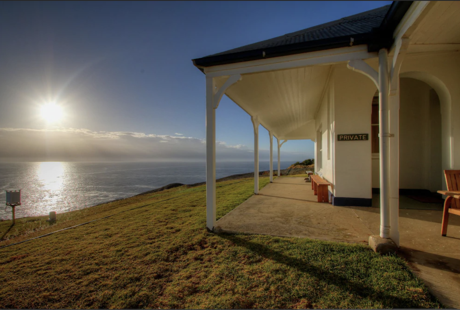 Montague Island Lighthouse with sea and sun in the background