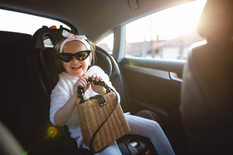 Joyful little girl playing around in her parents car