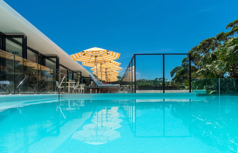 Crystal-clear rooftop pool at Bannisters Pavilion, Mollymook, NSW, surrounded by leafy treetops.