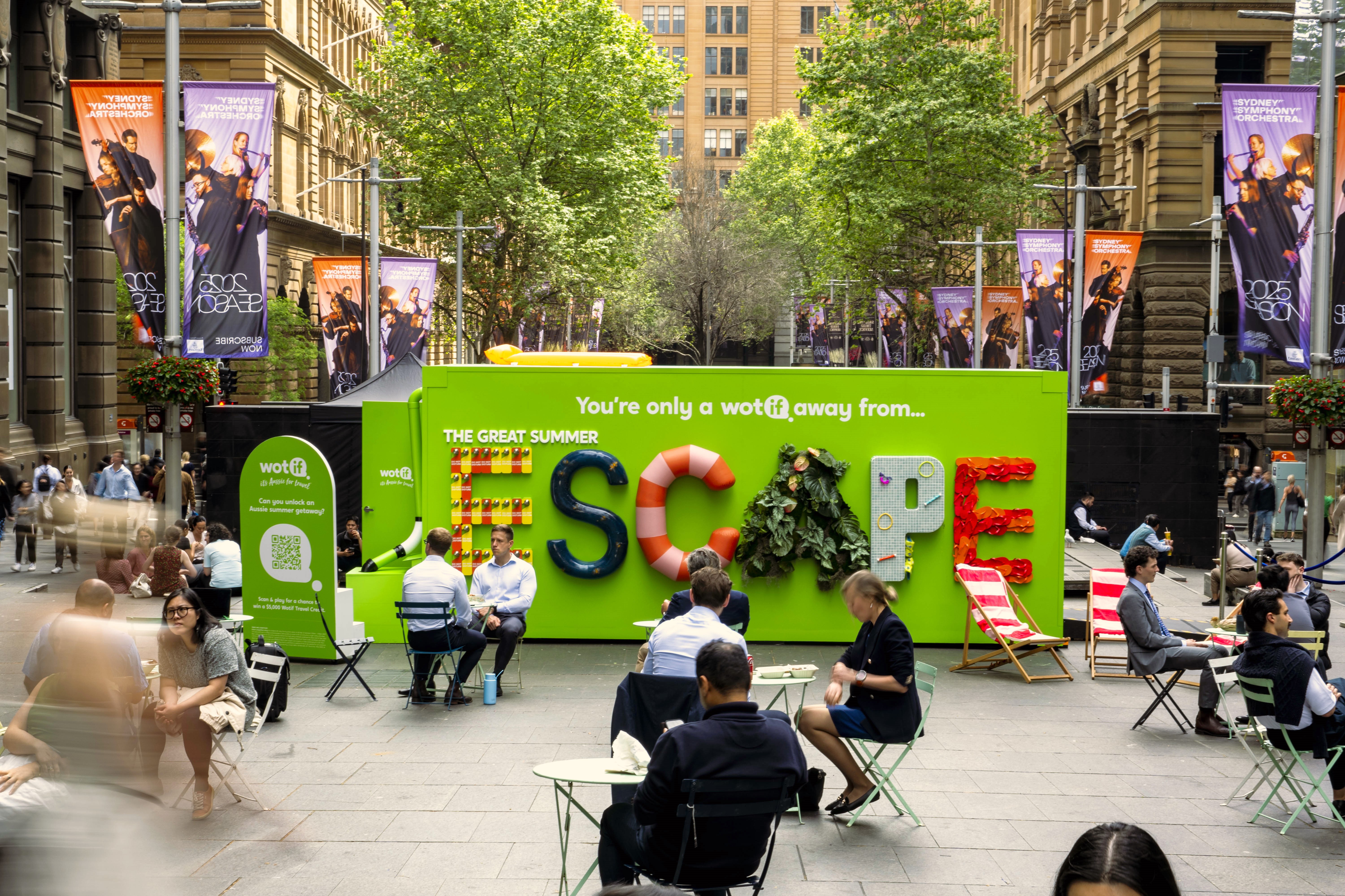 Wotif green coloured shipping container converted into a pop-up experience, situated in an open CBD courtyard surrounded by people drinking coffee and eating