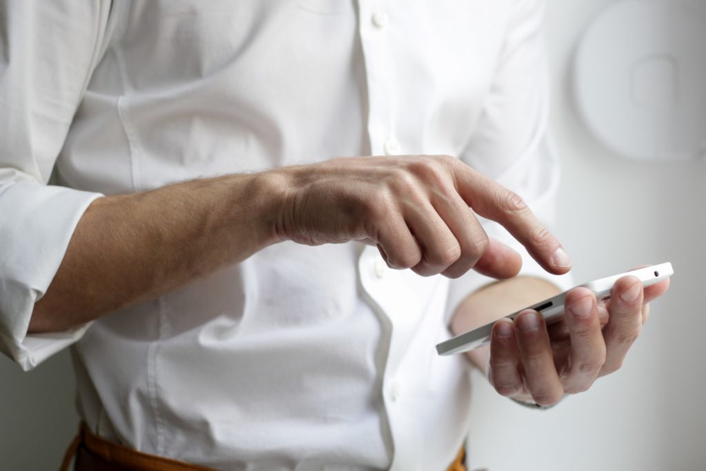 A male accountant wearing a white shirt using an app on his phone