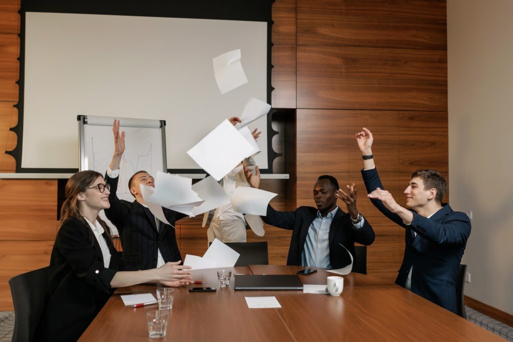 A group of employees in a meeting throwing paper into the air