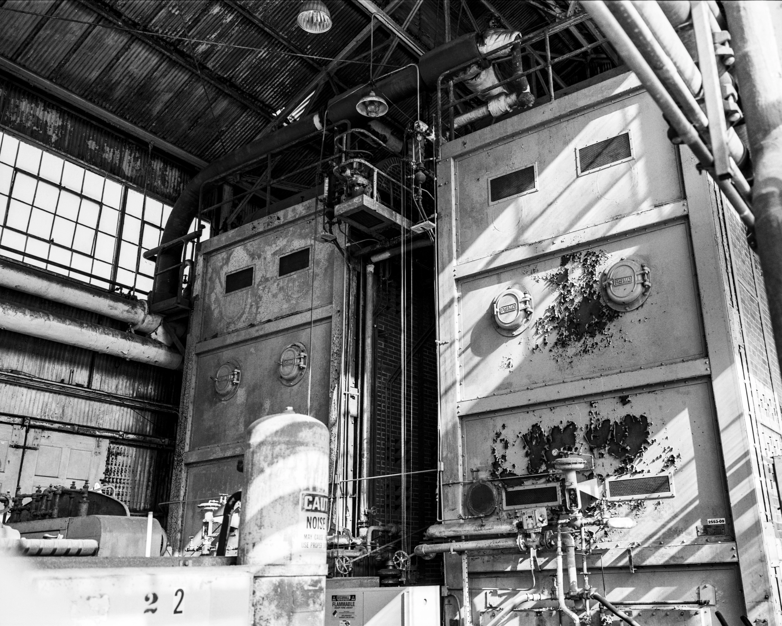 A black-and-white photograph of abandoned industrial equipment with a large brick furnace.