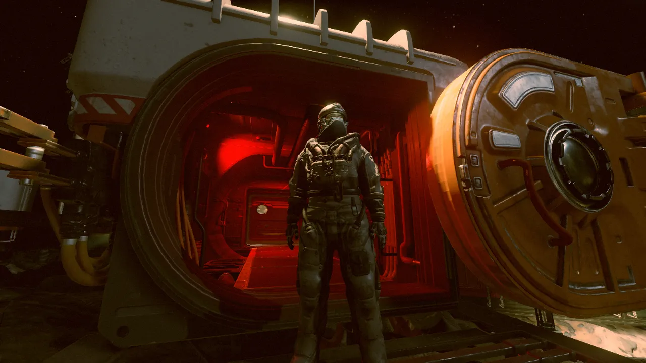 An astronaut stands, looking up at the night sky, in the open doorway of an airlock flooded with red light