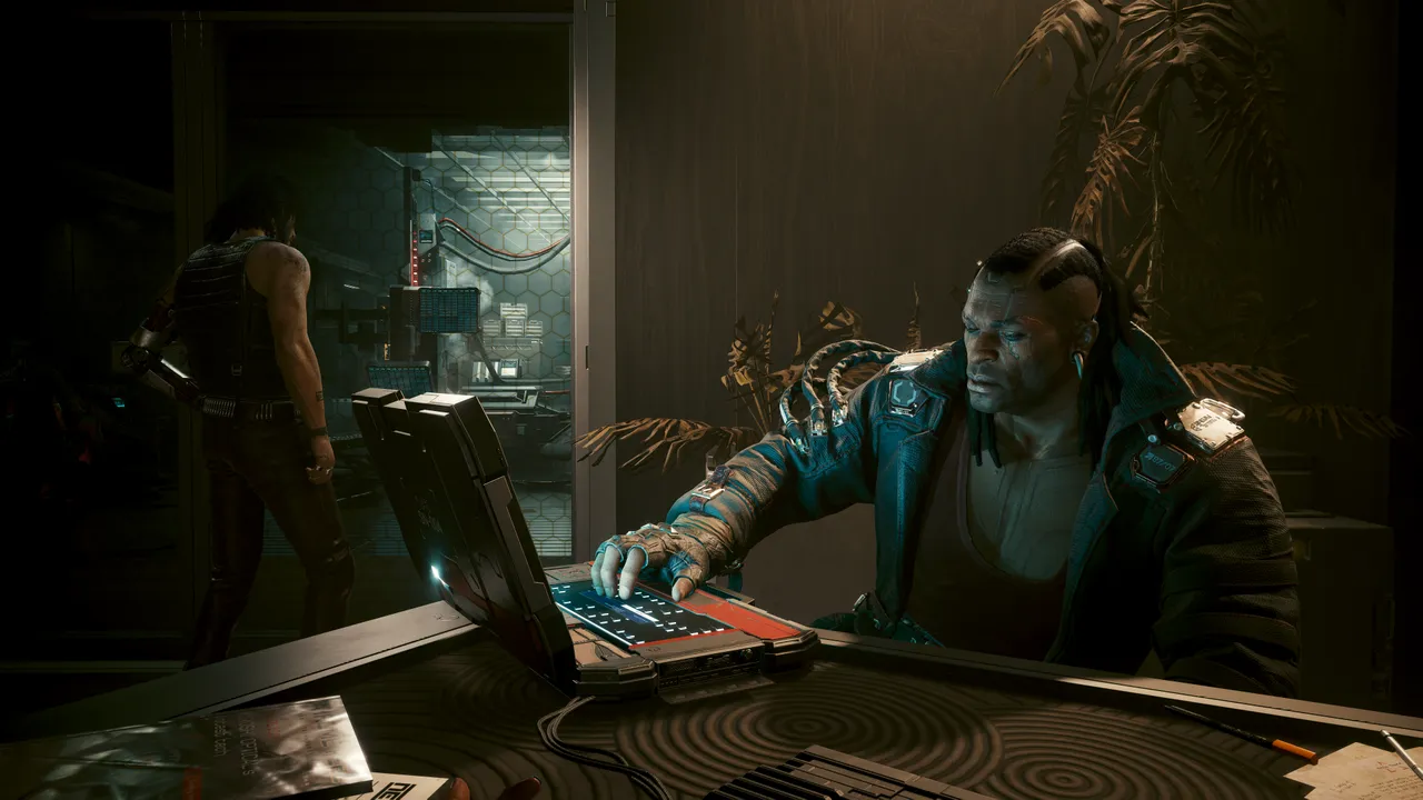 Placide browsing a laptop while Johnny looks into a locked room