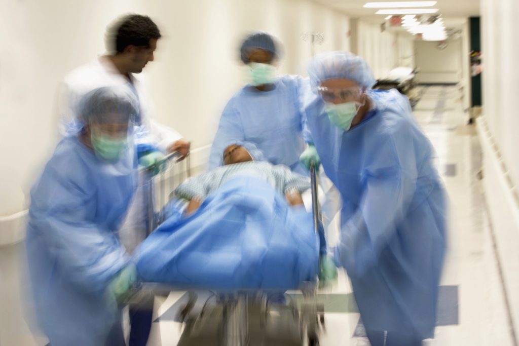 Doctor and assistants with patient on Hospital Gurney in hospital corridor