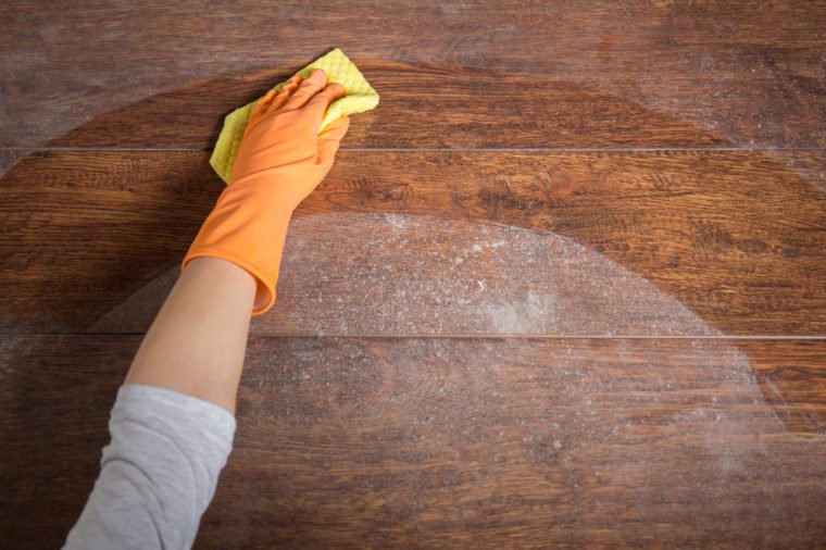 Close-up of hand cleaning wooden table with dishrag