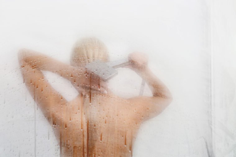 Beautiful young woman washing body in a shower