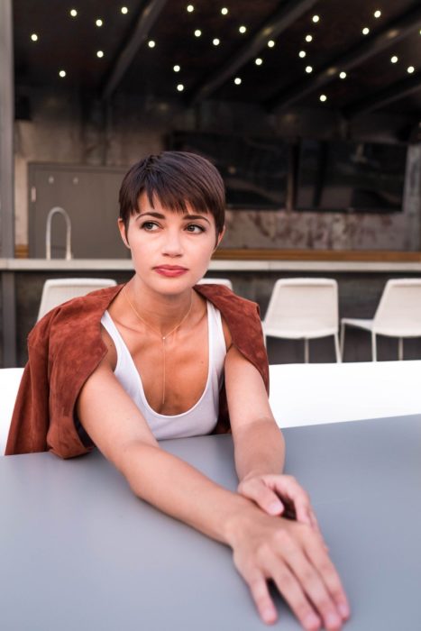 Chica con un corte pixi sentada en un restaurante posando para una fotografía 