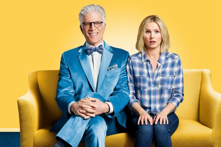 Hombre y una mujer sentados en un sofá sonriendo, escena promocional de la serie The Good Place