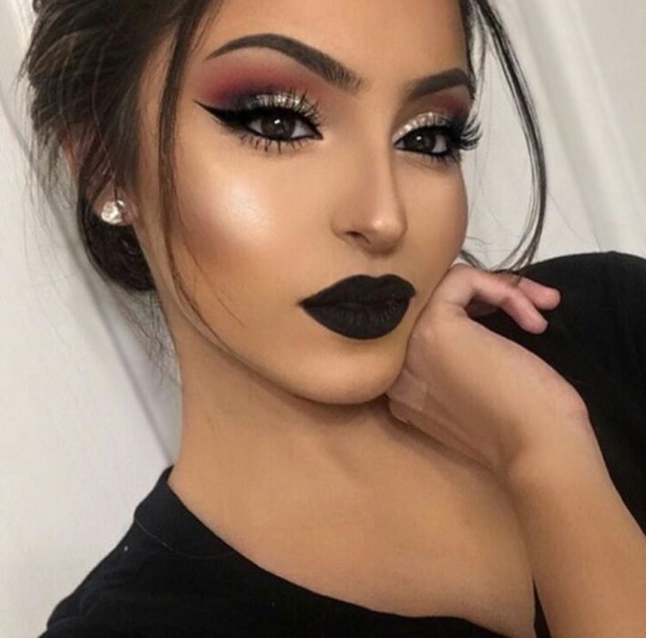 Chica usando una sombra de ojos brillante con unos labios color verde oscuro mate 