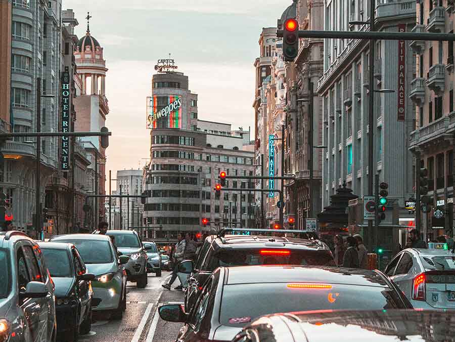 El carrer Gran Via de Madrid a la tarda amb l'edifici Schweppes en el centre i nombrosos cotxes