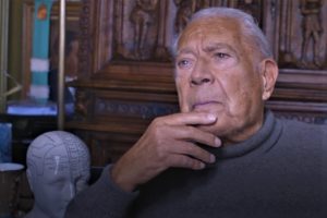 gros plan de Michel Jouvet à 90 ans- il est assis dans son bureau, se tenant le menton avec une main de façon pensive