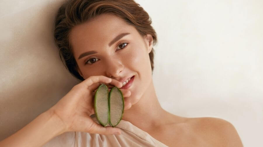 woman holding two slices of aloe vera