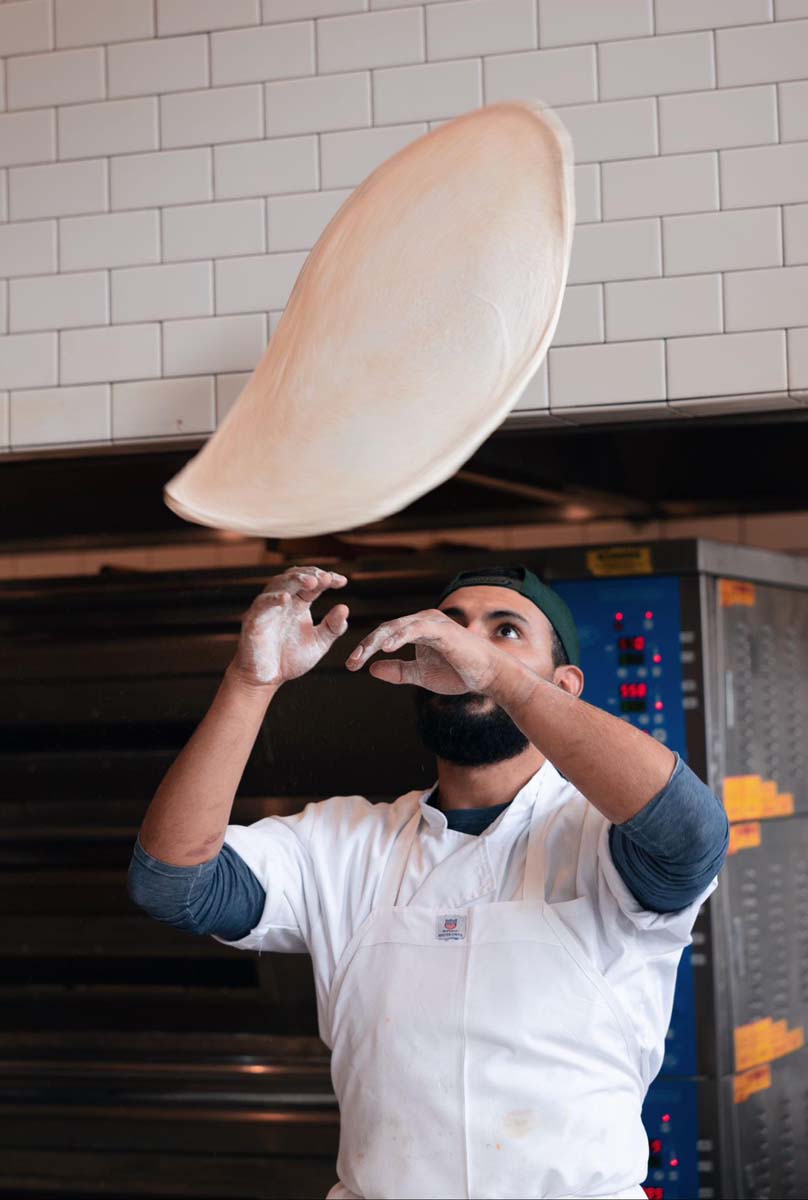 a chef tossing pizza dough into the air