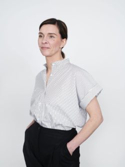 Cap sleeve shirt with vertical stripes, worn by a model with hands in pockets.