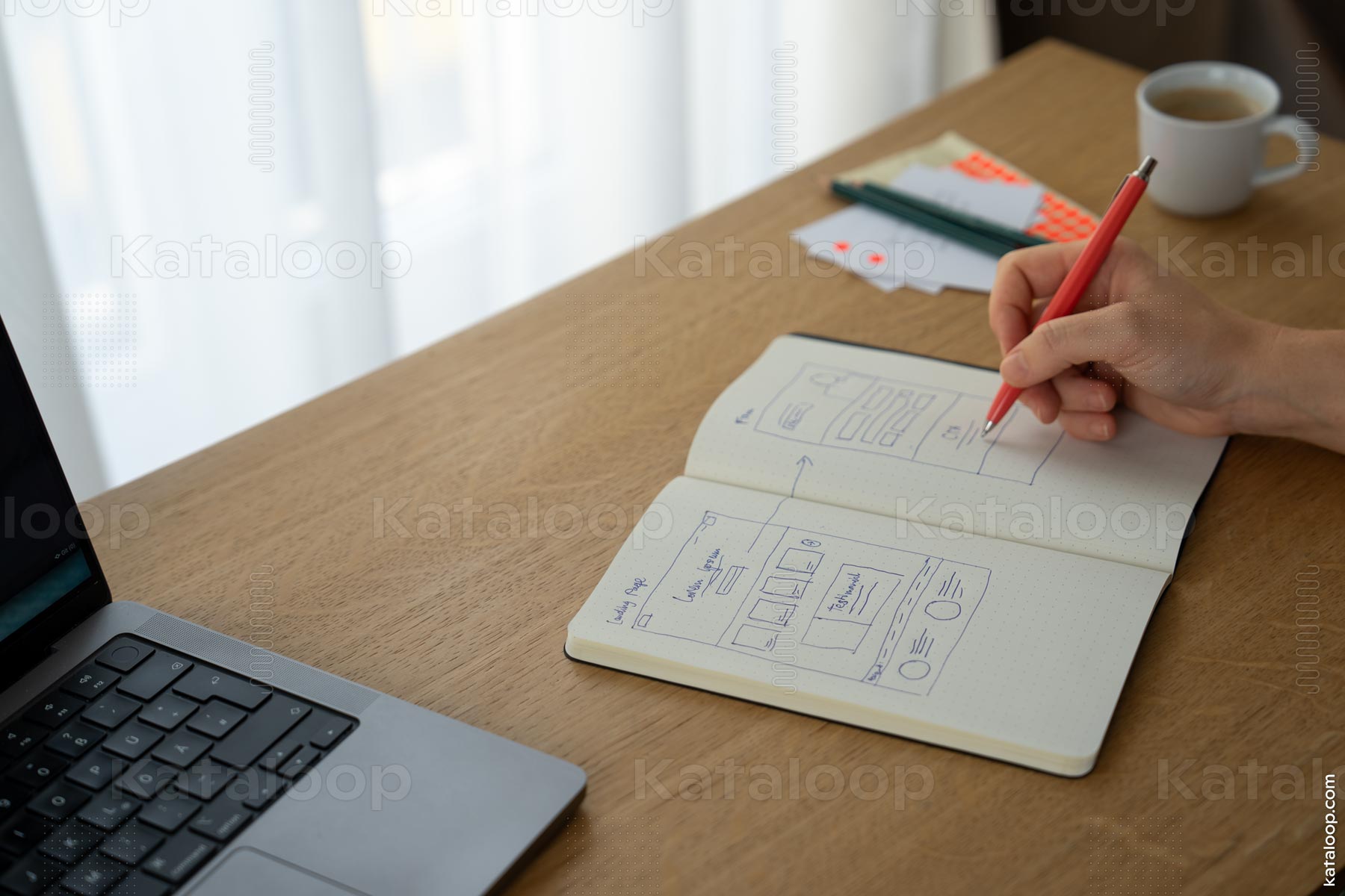 Skizzieren von Webdesign auf Notizbuch mit Laptop und Kaffee
