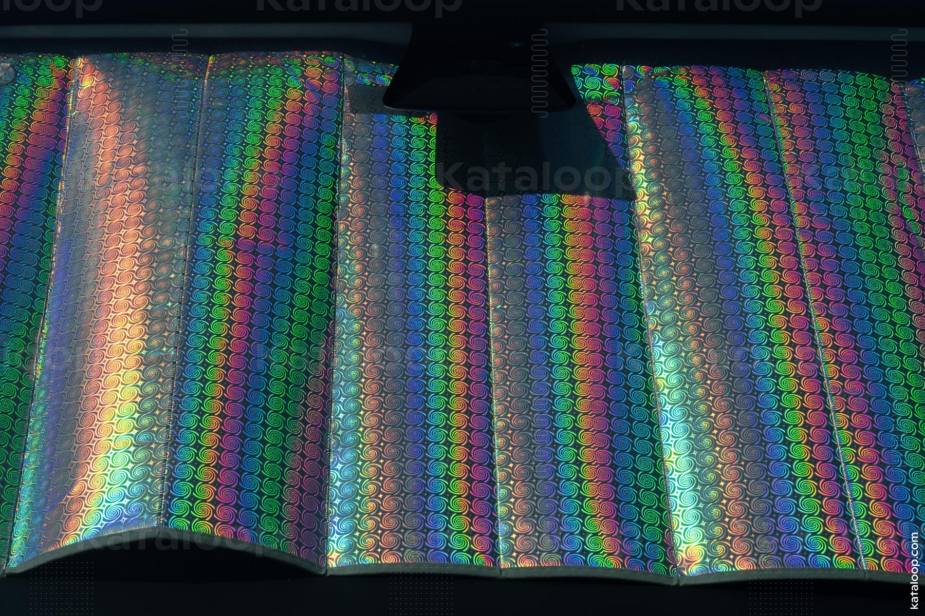 This image captures a close-up view of a reflective surface with vibrant holographic patterns. The patterns consist of repeating swirls that display a spectrum of colors when exposed to light. The effect creates a mesmerizing and futuristic appearance.