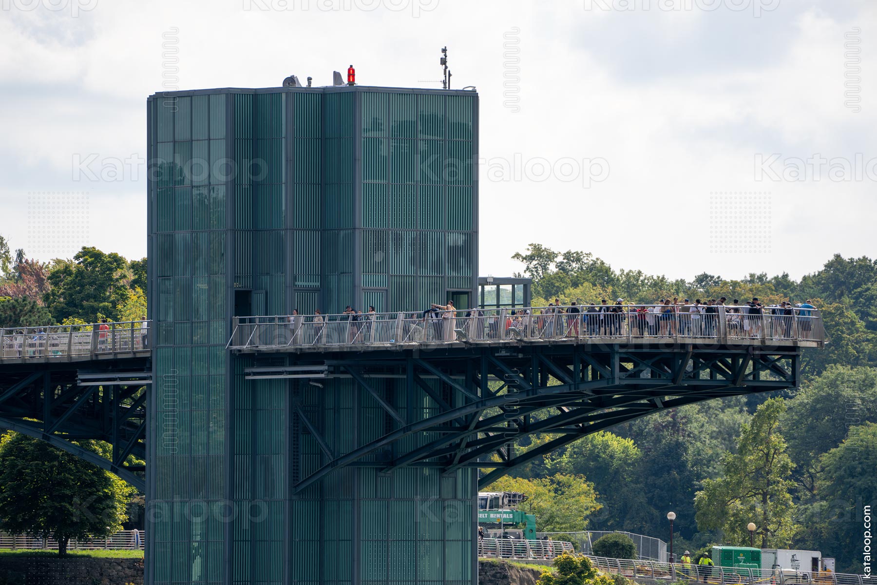 This image captures the bustling Niagara Falls Observation Tower, filled with visitors. Tourists can be seen leaning on the railings, taking in the panoramic views of the surrounding landscape and the famous waterfalls. The tower's distinctive architecture and the natural backdrop provide a striking contrast.