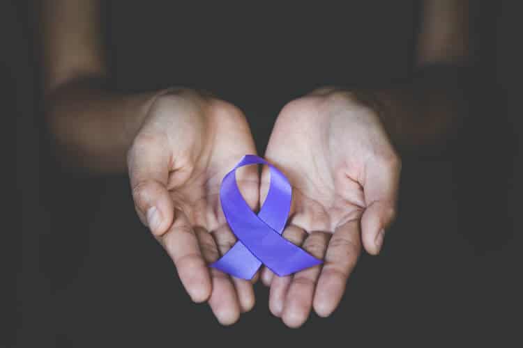 A person holding a purple ribbon in honor of Alzheimer’s and Brain Awareness Month.