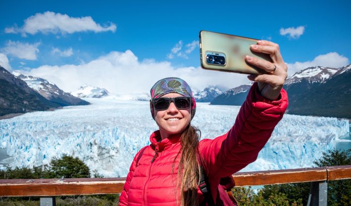 Una persona tomandose una selfie con los glaciares del Calafate de fondo
