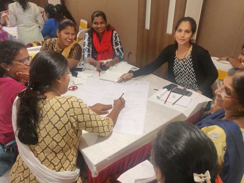 A group of women sitting around a table, working on a chart