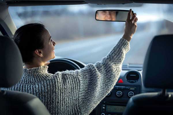 femme qui règle son rétroviseur voiture