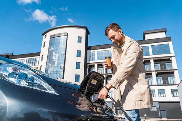 homme qui charge véhicule électrique café à la main