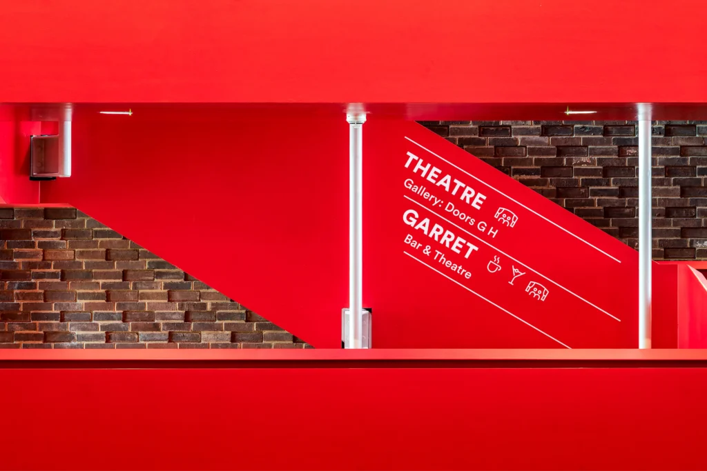 Way finding signage on red staircase from Storyhouse Chester