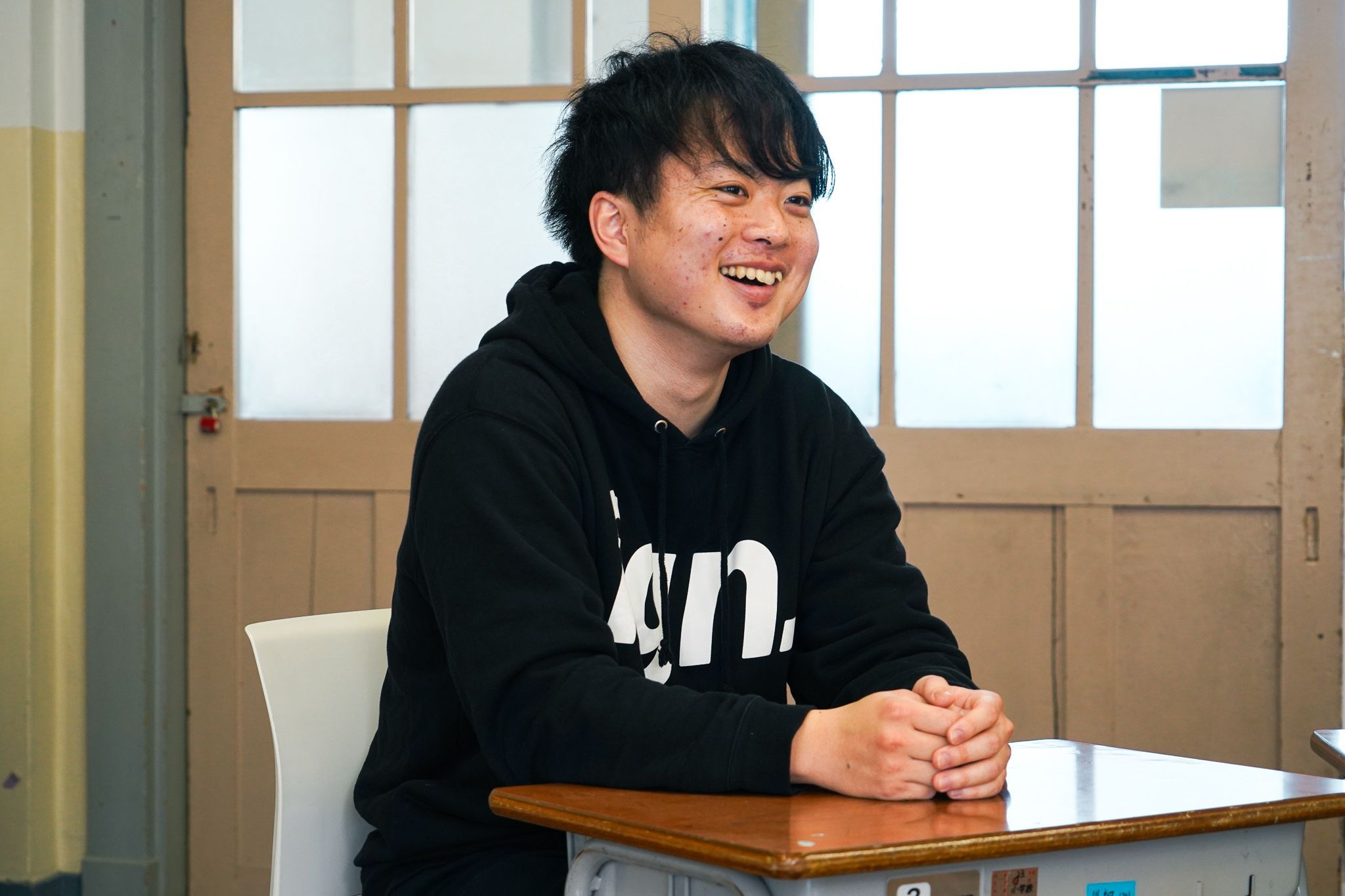 生徒用机に手を乗せ、笑顔で会話に参加する崎山さん