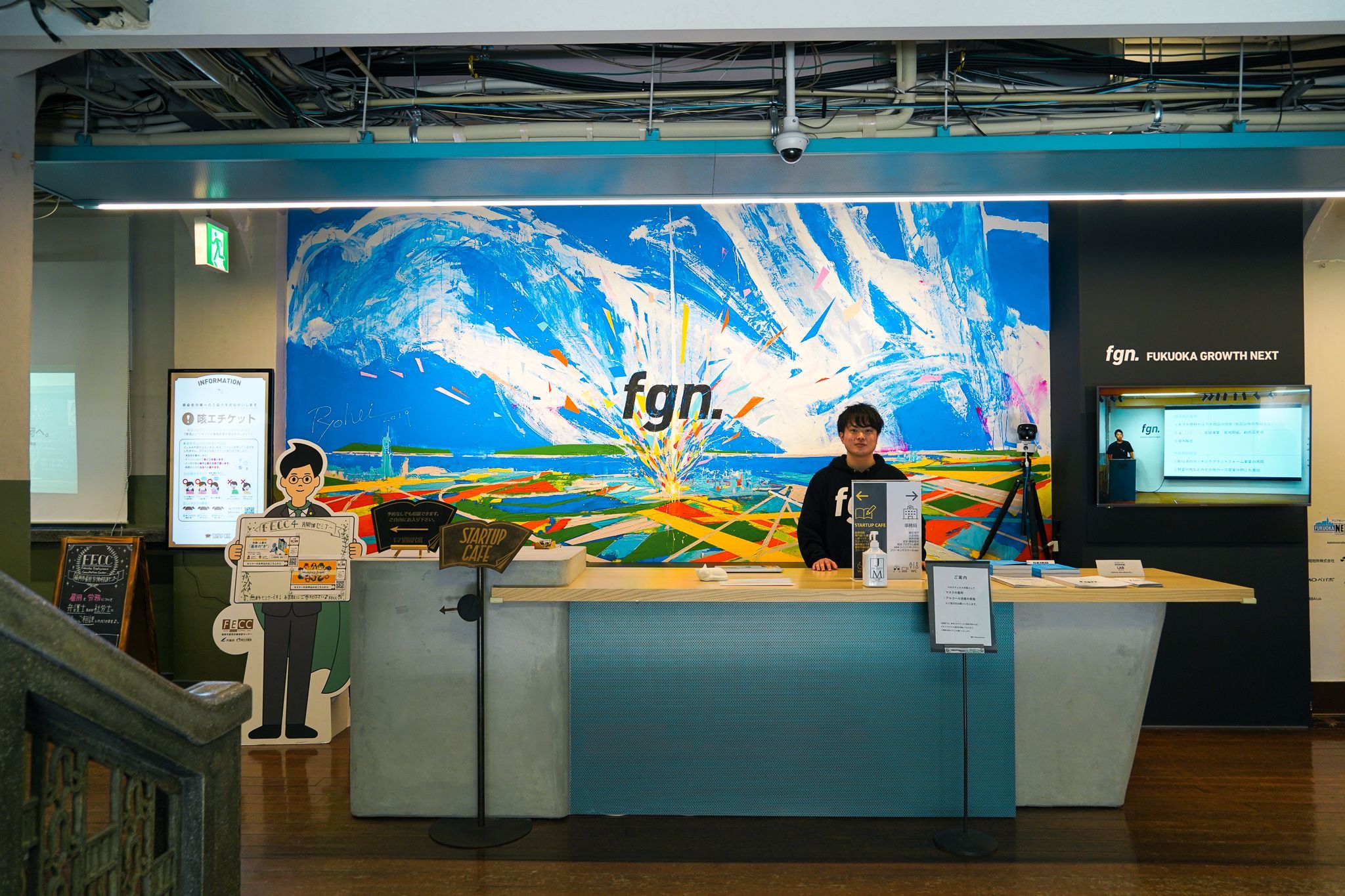 FGNのフロントカウンターで、来訪者を出迎える崎山さんの様子