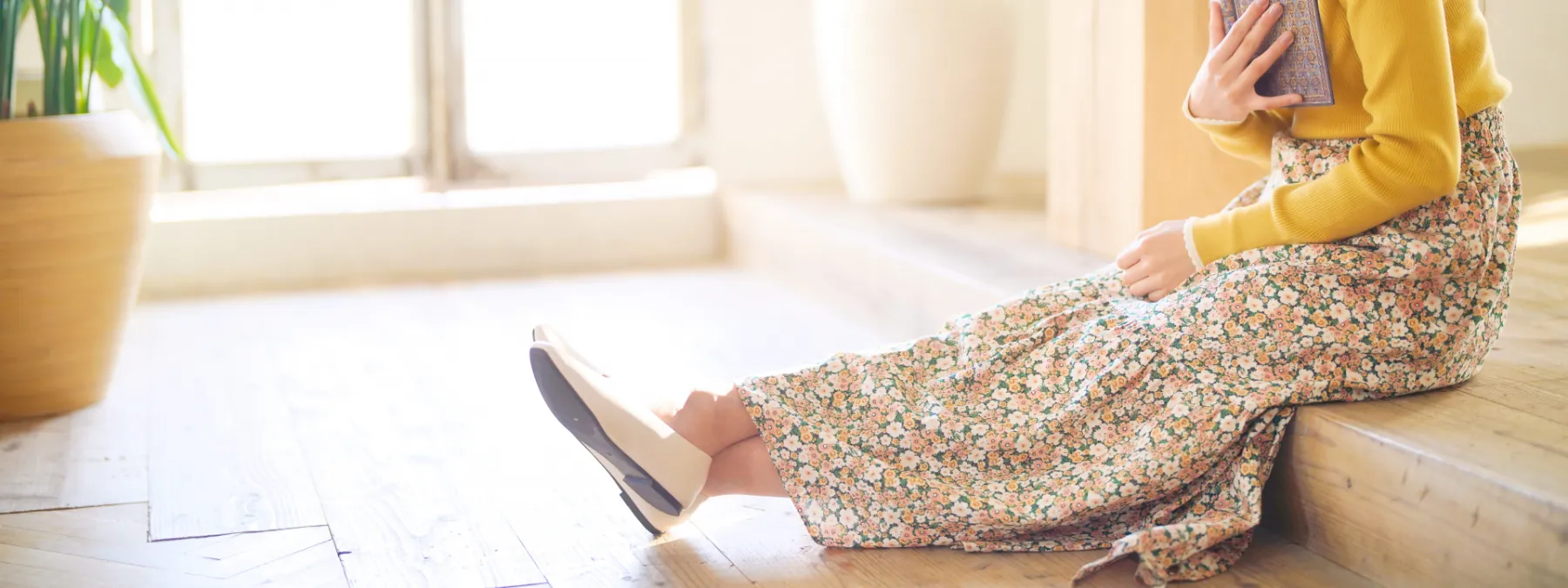 本を持って足を伸ばして段差に座っている女性